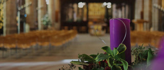 Purple Advent candle and wreath in church.