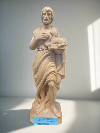 Statue of a classical figure holding a book on a shelf with a dark background