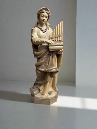 Statue of a woman playing a keyboard on a shelf with a wooden background