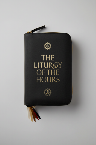 A black leather zippered journal titled 'THE LITURGY OF THE HOURS' in gold lettering, featuring decorative gold emblems and a multi-colored tassel bookmark, shown on a neutral gray background.